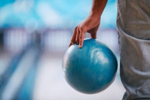 young man in jeans holding bowling ball